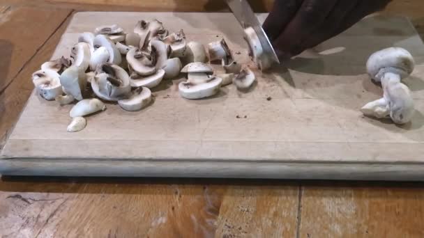 Etnia pessoa cortando cogumelos em uma tábua de corte de madeira — Vídeo de Stock