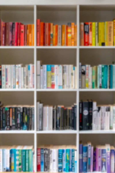 Imagem desfocada da estante de madeira branca preenchida com livros — Fotografia de Stock