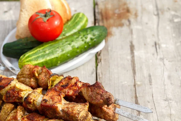 Shish kebab on skewers. On a wooden table with fresh vegetables. kebab with copyspace — Stock Photo, Image