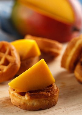 Daire mini waffle ahşap kesme tahtası üzerinde mango ile