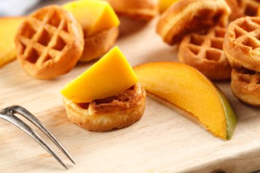 Daire mini waffle ahşap kesme tahtası üzerinde mango ile