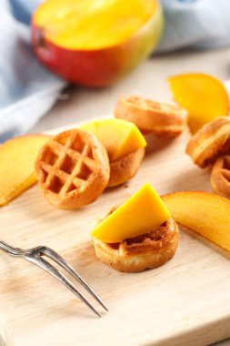 Daire mini waffle ahşap kesme tahtası üzerinde mango ile