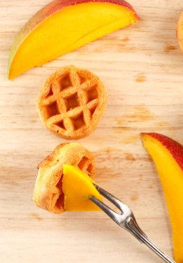 Daire ahşap kesme tahtası üzerinde mango ile mini waffle. Üstten görünüm