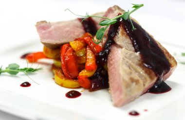 Restoran menü için beyaz tabakta sebze ızgara ve kiraz soslu biftek