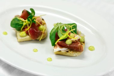 Bruschetta hamon ve limon sosu ve marul beyaz plaka üzerinde