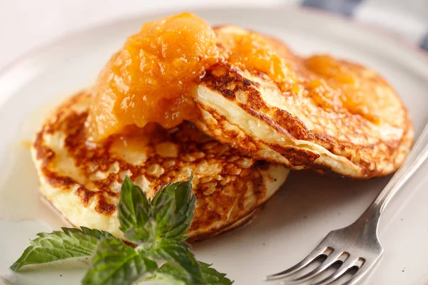 Quark-Pfannkuchen, Syrniki, Quark-Krapfen. Frühstück auf weißem Hintergrund Käsekuchen und Marillenmarmelade. — Stockfoto