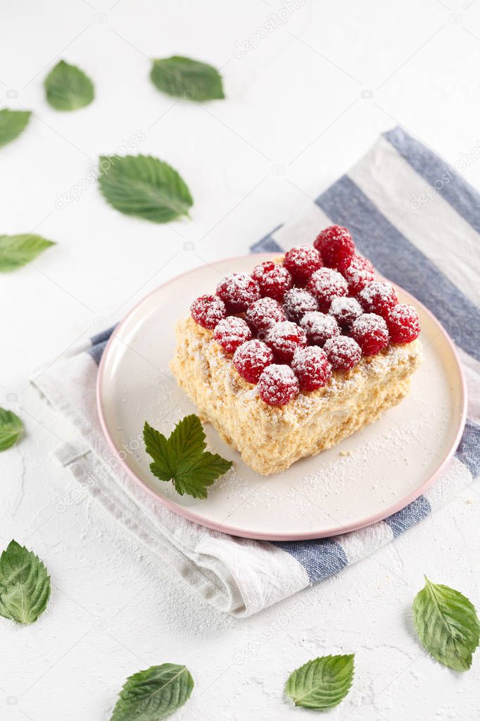 Napoleon cake with raspberries on a white table