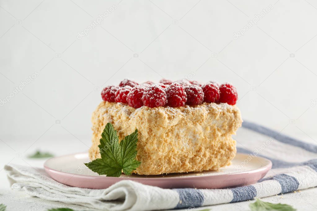 Napoleon cake with raspberries on a white table