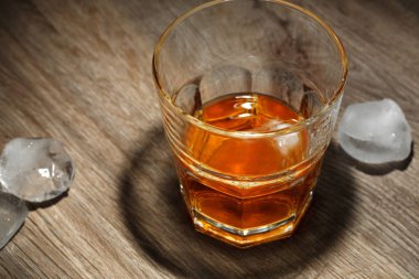 Ahşap masa buz küpleri ile alkollü içecek bir bardak. Siyah arka plan üzerine bardakta viski
