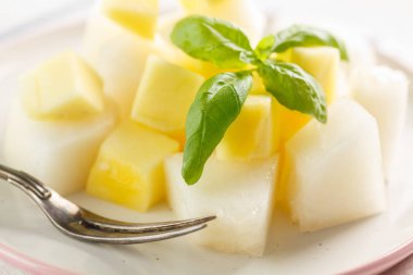 meyve salatası. Mango ve beyaz arka plan üzerinde bir tabakta Fesleğenli kavun