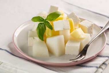 Peynirli meyve salatası. Mango, kavun peynir ve fesleğen ile beyaz arka plan üzerinde bir plaka üzerinde