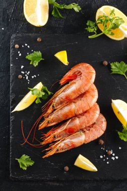 kerevitleri baharatlar, limon ve otlar siyah bir arka plan ile. Baharatlar ve limon ile kaplan karides. Üstten görünüm.
