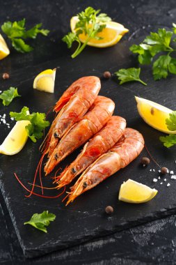 kerevitleri baharatlar, limon ve otlar siyah bir arka plan ile. Baharatlar ve limon ile kaplan karides. Üstten görünüm.