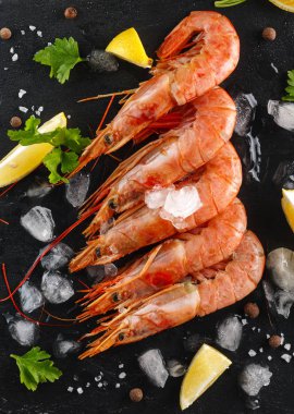 kerevitleri veya karides baharatlar, limon ve otlar siyah bir arka plan ile. Üstten görünüm. Flatlay