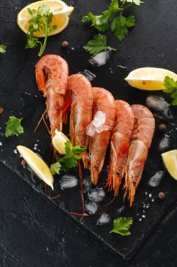 kerevitleri veya karides baharatlar, limon ve otlar siyah bir arka plan ile. Üstten görünüm. Flatlay