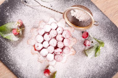 Ahududu süslemeli ve tamamen pudra şekerli kek.