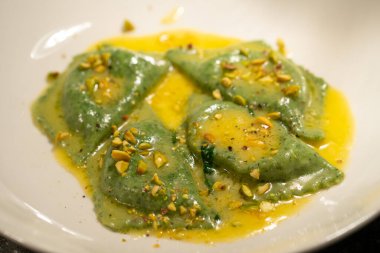 Taştan bir masada ıspanaklı ve fındıklı yeşil ravioli.