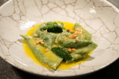 Taştan bir masada ıspanaklı ve fındıklı yeşil ravioli.