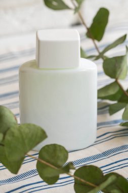 Beyaz tekstil arka planında beyaz plastik kozmetik şişe