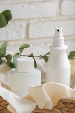 Tekstil arka planında beyaz kozmetik şişeleri. İçerik.