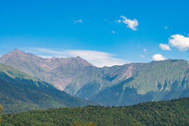 Dağ manzarası. Mavi gökyüzüne karşı yeşil dağlar.