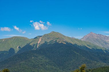 Dağ manzarası. Mavi gökyüzüne karşı yeşil dağlar.