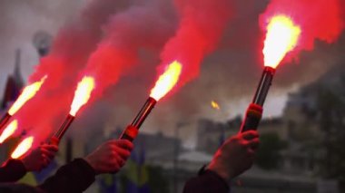 Ellerinde yanan ateşler tutan protestocular. Yakından yanan ve tüten meşaleler tutan eller. Şehrin sokaklarında ayaklanmalar ve holiganlık. Ayaklanmalar sırasında polisle çatışmalar