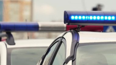 Parlak teşhirci polis arabası şehrin caddesinde duruyor. Polis yoldaki arabanın ışıklarını yaktı. Geçmişi. Yakın plan. Polis olay yerinde.