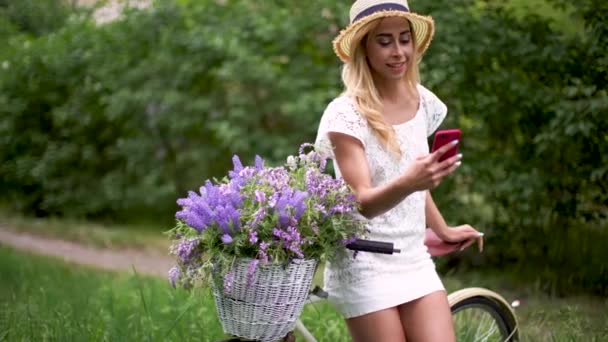 Menina bonita com bicicleta vintage e flores no fundo da cidade na luz do sol ao ar livre . — Vídeo de Stock