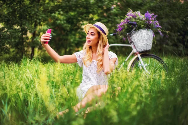 Bella ragazza con bicicletta vintage e fiori sulla città ba — Foto Stock