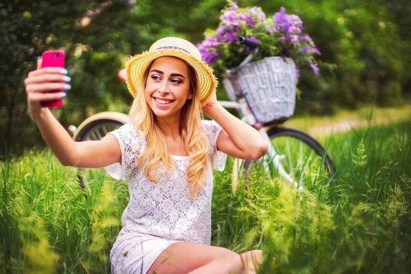 Mooi jong meisje met vintage fiets en bloemen op stad ba — Stockfoto
