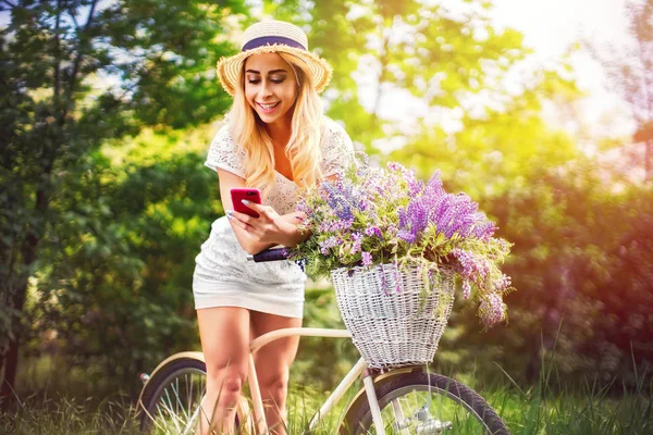 Bella ragazza con bicicletta vintage e fiori sulla città ba — Foto Stock