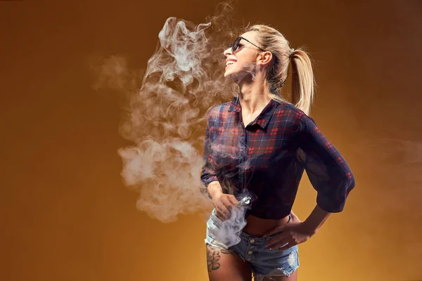 Woman standing and vaping in studio — Stock Photo, Image