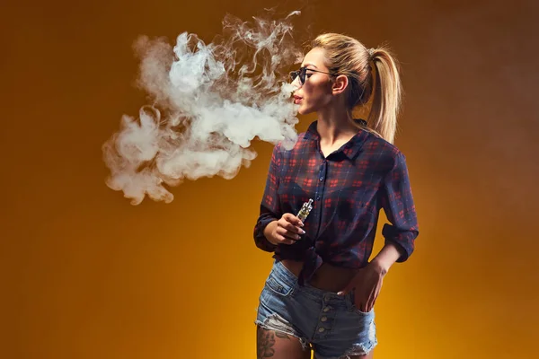 Woman standing and vaping in studio — Stock Photo, Image