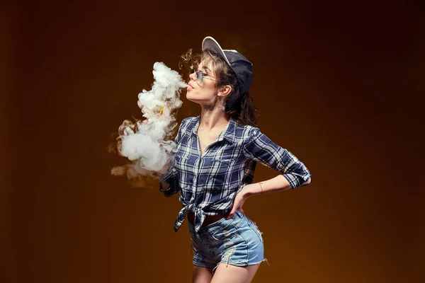 Woman standing and vaping in studio — Stock Photo, Image