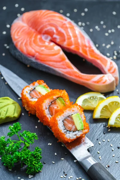 Sushi served on japanese knife on a black slate plate