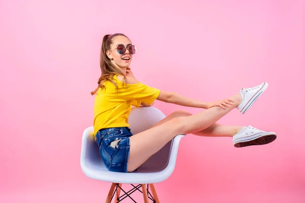Menina adolescente brincalhão sentado na cadeira com as pernas levantadas — Fotografia de Stock