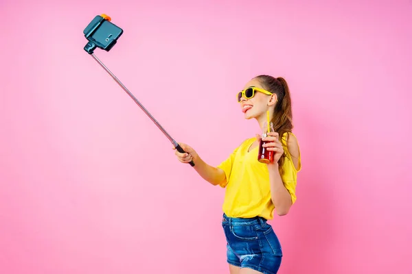 Usmívající se dospívající dívka s nápojem, takže selfie stick — Stock fotografie