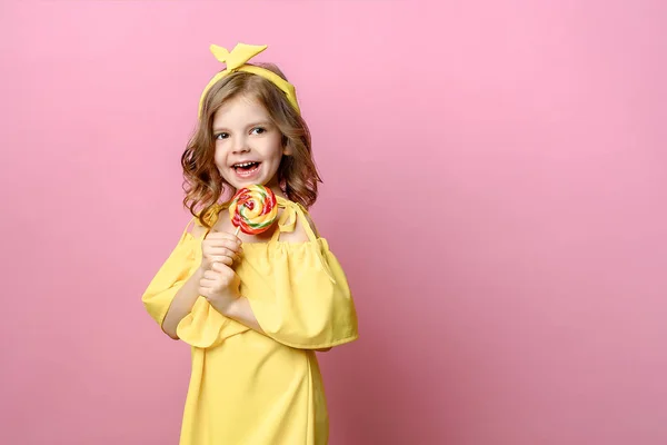 Прекрасна маленька дівчинка з цукерками на рожевому — стокове фото