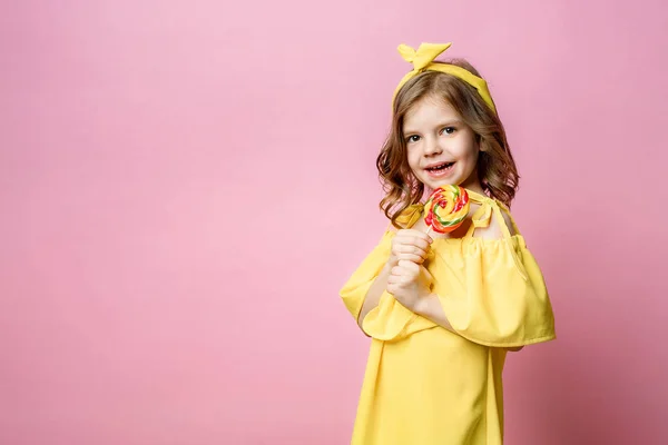 Милая маленькая девочка с конфетами на розовом — стоковое фото