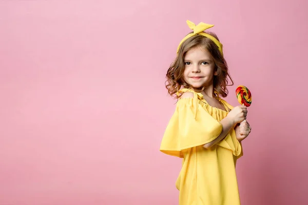 Прекрасна маленька дівчинка з цукерками на рожевому — стокове фото
