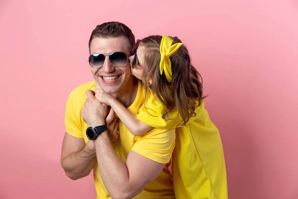 可爱的爸爸和女儿在黄色和太阳镜拥抱彩色粉红色的背景。暑期理念. — 图库照片