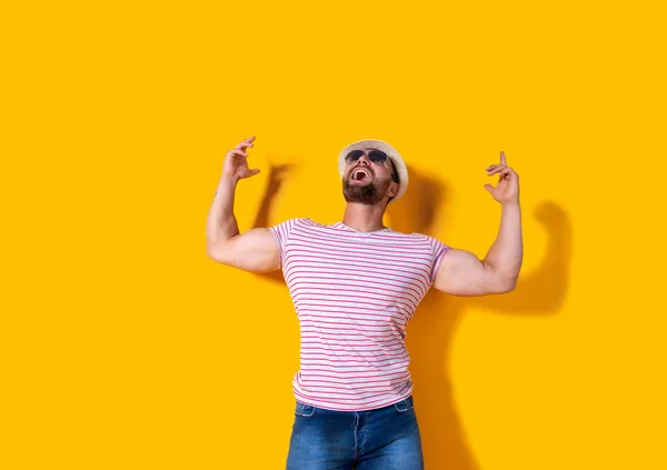 Hombre barbudo con sombrero y gafas de sol posando con las manos arriba . — Foto de Stock