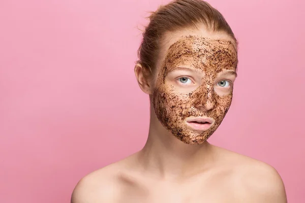 Face Skin Scrub. Retrato de modelo feminino sorridente sexy aplicando máscara de café natural, esfoliação facial na pele facial. Closeup de bela mulher feliz com rosto coberto com produto de beleza . — Fotografia de Stock