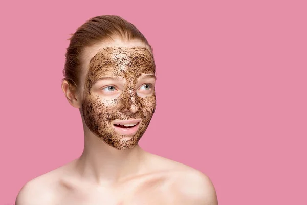 Face Skin Scrub. Portrait Of Sexy Smiling Female Model Applying Natural Coffee Mask, Face Scrub On Facial Skin. Closeup Of Beautiful Happy Woman With Face Covered With Beauty Product.