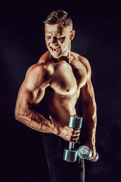 Hombre musculoso concentrado haciendo ejercicio con mancuerna —  Fotos de Stock