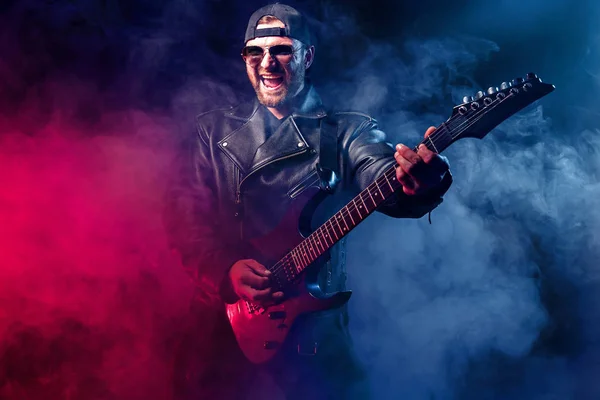 Heavy metal musician is playing electrical guitar. Shot in a studio. — Stock Photo, Image