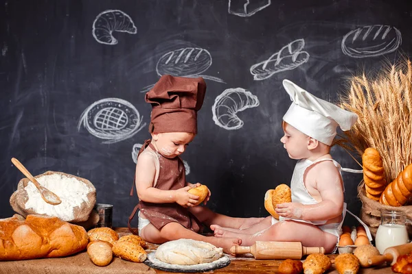 Charming little toddlers in aprons on table with bread Stock Photo