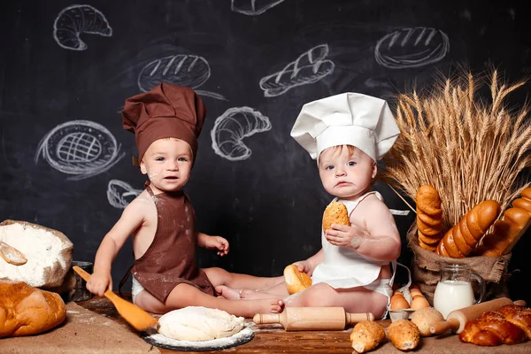 Charming little toddlers in aprons on table with bread Stock Image