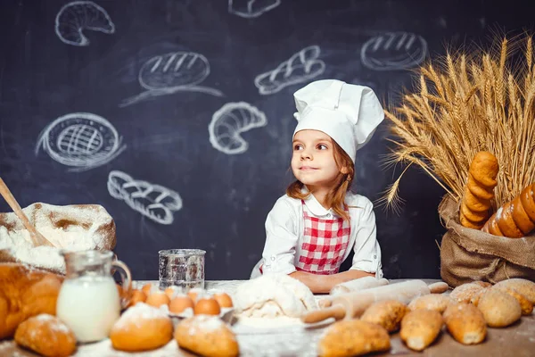 Bedårande liten flicka i kockmössa att göra degen — Stockfoto